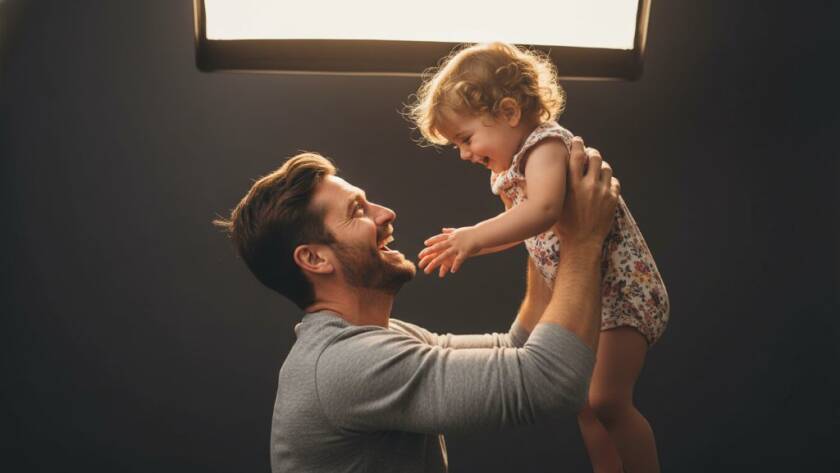 An epic, emotionally resonant photograph of a Botanic Ridge family during a personalised studio photography session, showcasing a parent holding a child in a moment of pure joy and connection, with dramatic backlighting and professional colour grading.
