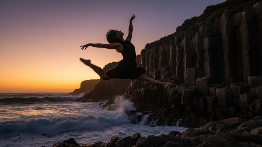 A professional photograph capturing a dancer in an epic, dynamic leap over the rugged coastline near Portland, Victoria, showcasing the power of Portland Victoria dynamic dance photography with dramatic sunset lighting.