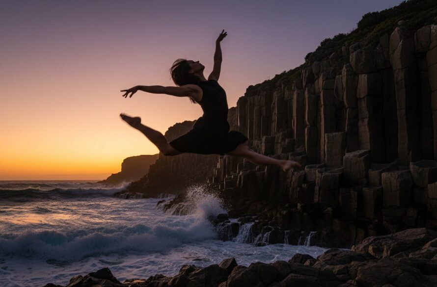 A professional photograph capturing a dancer in an epic, dynamic leap over the rugged coastline near Portland, Victoria, showcasing the power of Portland Victoria dynamic dance photography with dramatic sunset lighting.