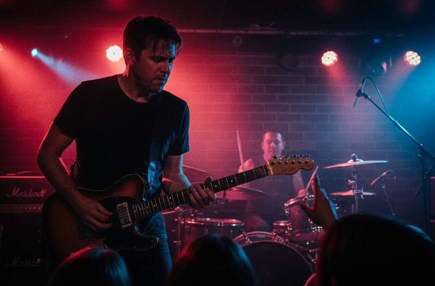A dynamic, wide-angle shot of a lead guitarist mid-shred, bathed in dramatic red and blue stage lights at a Doncaster venue, perfectly showcasing professional concert photography Doncaster Victoria with energy and passion.