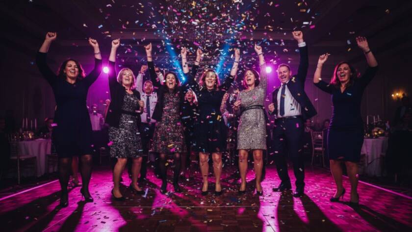 A wide-angle, vibrant shot of guests celebrating under colourful lights at a Dandenong North community hall, perfectly capturing professional Dandenong North party photography unforgettable moments with laughter and movement.