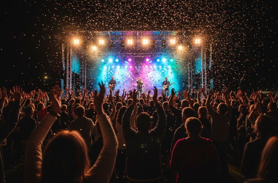 A dynamic, wide-angle shot of a joyous community festival in Brown Hill, Victoria, with a local band performing on a brightly lit stage and an ecstatic crowd cheering, embodying the spirit of professional event photography Brown Hill Victoria, captured at its peak moment.