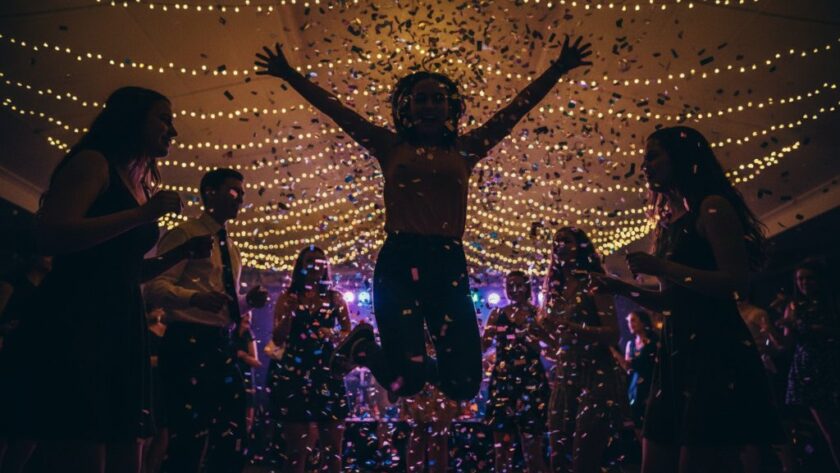 A candid, high-energy photograph capturing an epic moment of joyful laughter and dancing at a vibrant evening celebration in Sale, Victoria, expertly showcasing professional party photography in Sale Victoria vibrant celebrations. Dynamic lighting illuminates guests mid-action, with confetti subtly falling, creating a professional, colour-graded scene of pure revelry.