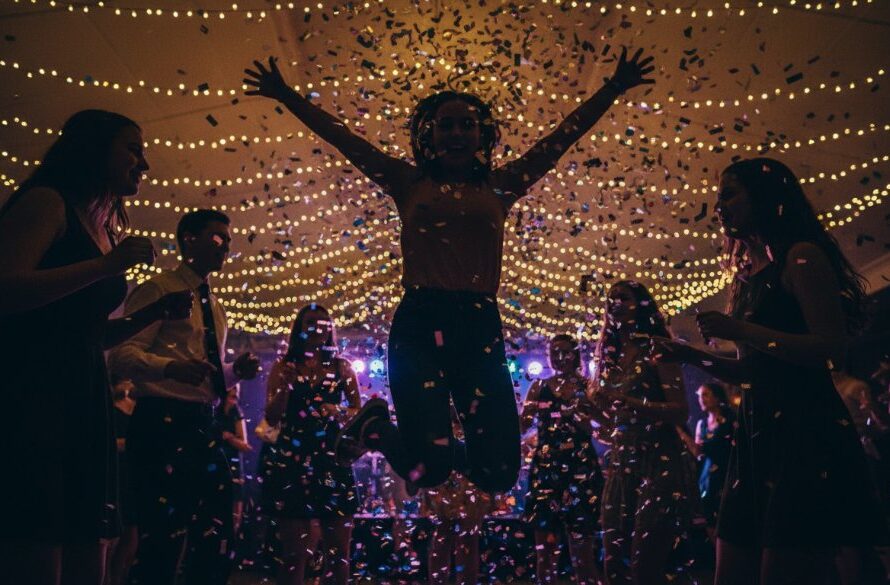 A candid, high-energy photograph capturing an epic moment of joyful laughter and dancing at a vibrant evening celebration in Sale, Victoria, expertly showcasing professional party photography in Sale Victoria vibrant celebrations. Dynamic lighting illuminates guests mid-action, with confetti subtly falling, creating a professional, colour-graded scene of pure revelry.
