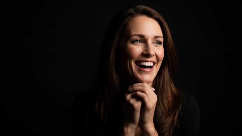 Dramatic black and white close-up of a young woman smiling genuinely in a professional studio setting, capturing an epic moment of connection, representing professional studio photography Gisborne Victoria for timeless portraits.