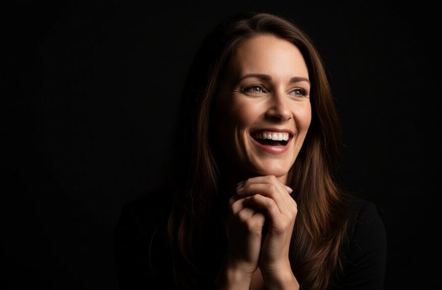 Dramatic black and white close-up of a young woman smiling genuinely in a professional studio setting, capturing an epic moment of connection, representing professional studio photography Gisborne Victoria for timeless portraits.