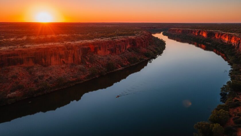 An epic aerial shot of the tranquil Murray River at sunset near Red Cliffs, Victoria, showcasing the vibrant red cliffs and the winding river under a dramatic, colourful sky, captured with Red Cliffs Victoria drone photography, evoking a sense of peaceful grandeur.