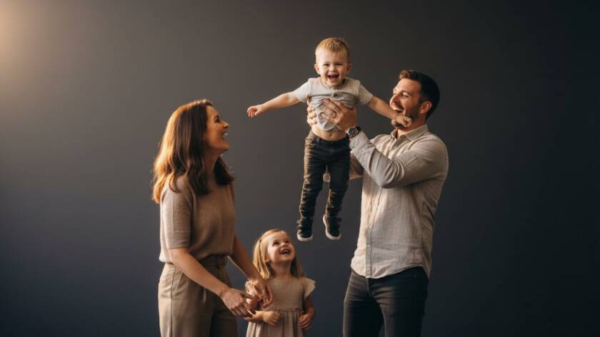 An emotionally resonant, epic moment photograph capturing a family laughing joyfully during a Ringwood Victoria bespoke family studio photography session, with dramatic backlighting and a warm, inviting atmosphere.