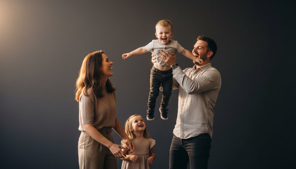 An emotionally resonant, epic moment photograph capturing a family laughing joyfully during a Ringwood Victoria bespoke family studio photography session, with dramatic backlighting and a warm, inviting atmosphere.