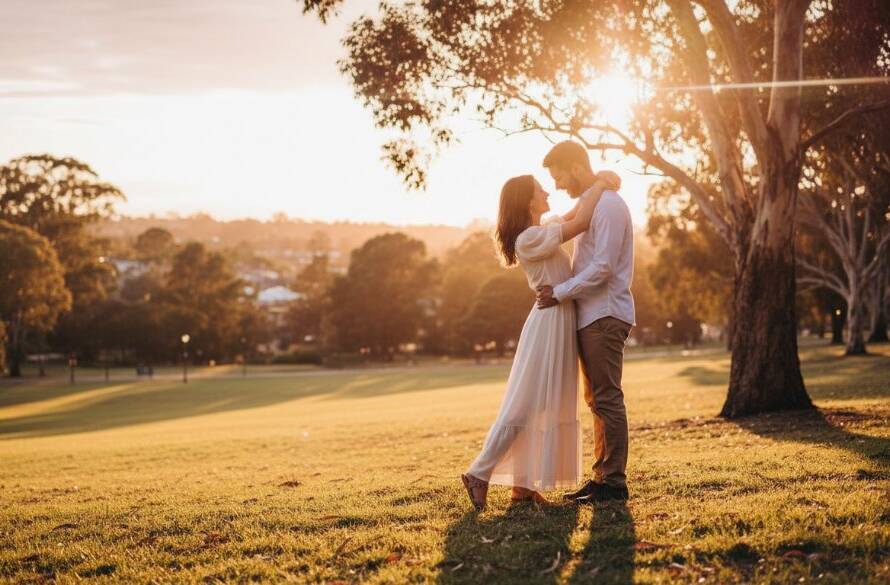 A couple sharing a tender embrace at sunset in a lush Nunawading park, bathed in golden hour light, creating romantic Nunawading engagement photos capturing genuine joy with a cinematic, epic moment feel.