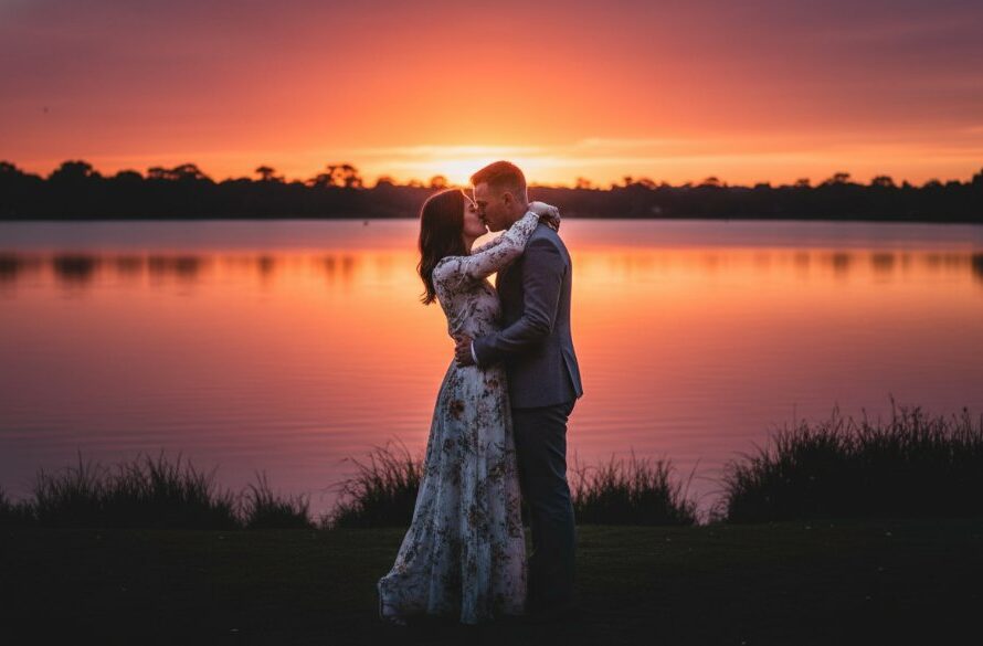 An epic moment captured during romantic pre-wedding photography in Alfredton, Victoria, featuring a couple embracing passionately under a dramatic, sunset-lit sky near the tranquil shores of Lake Wendouree, showcasing the breathtaking Australian landscape.