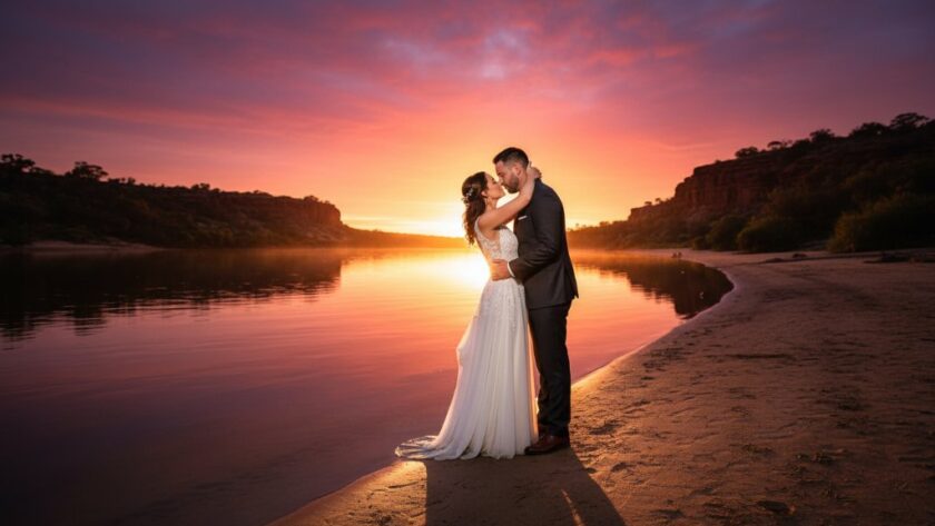 An epic, romantic Red Cliffs Victoria wedding photography sunsets shot featuring a newlywed couple silhouetted against a vibrant, golden orange sky over the Murray River, holding hands and looking into the distance, with a dramatic, cinematic feel.