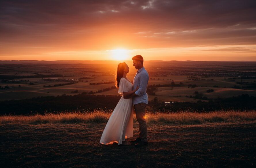 An epic moment captured during a romantic Wallan pre-wedding photography session, featuring a couple embracing passionately at sunset on a sprawling Wallan hilltop, bathed in golden light with the distant Dandenong Ranges visible, professional cinematic photography with dramatic colour grading.