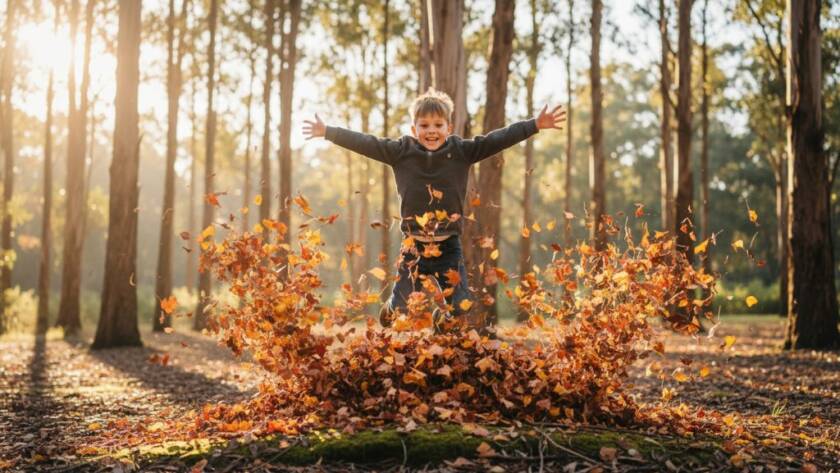 A professional photograph of a young child, around 5 years old, laughing joyfully as they run through a field of golden sun-drenched grass at Lysterfield Park, Rowville, with their parents' hands visible gently guiding them from behind, bathed in dramatic golden hour light, capturing Rowville family photography capturing authentic child joy.