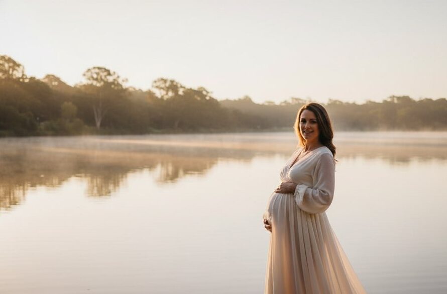 A pregnant woman glowing during a serene Eureka maternity photoshoot Victoria, standing gracefully at dawn near Lake Wendouree, with dramatic golden light filtering through trees, capturing an epic moment of anticipation and natural beauty with professional color grading.