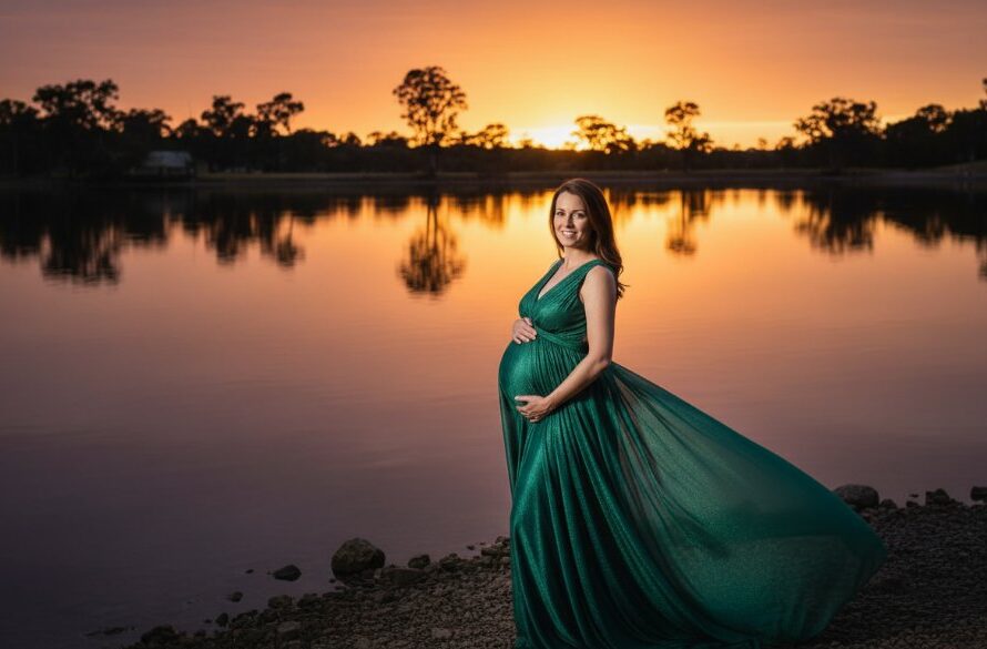 A breathtaking, professional photograph capturing a heavily pregnant woman in a flowing gown, silhouetted against a golden sunset over the tranquil Kialla lakeshore, embodying serene Kialla outdoor maternity photography, with dramatic lighting and ethereal mood.