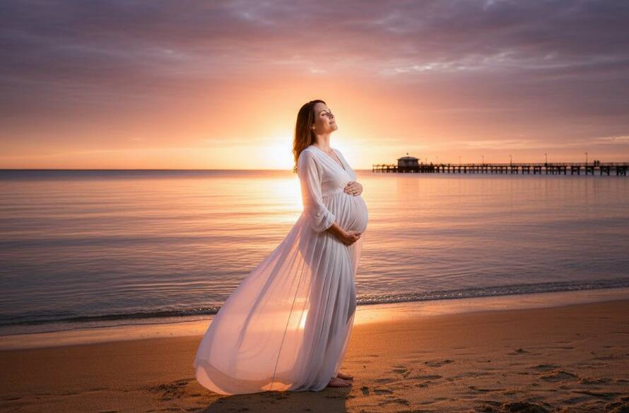 An expectant mother in a flowing gown stands silhouetted against a dramatic sunset at Edithvale Beach, her baby bump gently highlighted by the golden light, epitomizing serene maternity photography Edithvale beach Victoria.