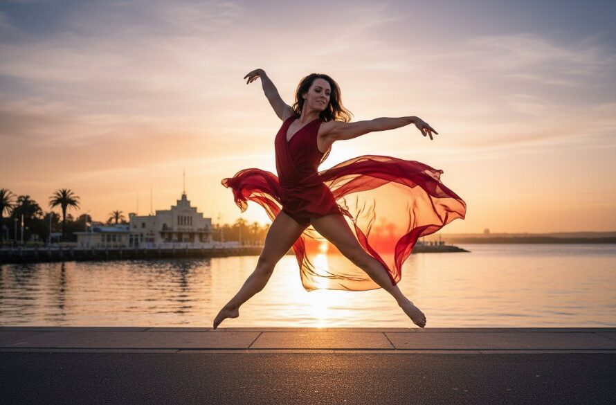 A professional photograph of a dancer performing an elegant leap against the vibrant, soft-focus backdrop of the Geelong Waterfront at sunset, perfectly capturing South Geelong dynamic dance photography for performing arts with dramatic backlighting and a sense of graceful power.
