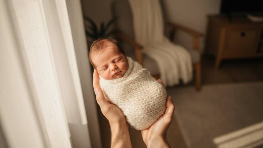 An intimate, heartwarming moment captured in St Albans newborn photography natural light, featuring a sleeping baby cradled by gentle parents' hands, bathed in soft, ethereal daylight.