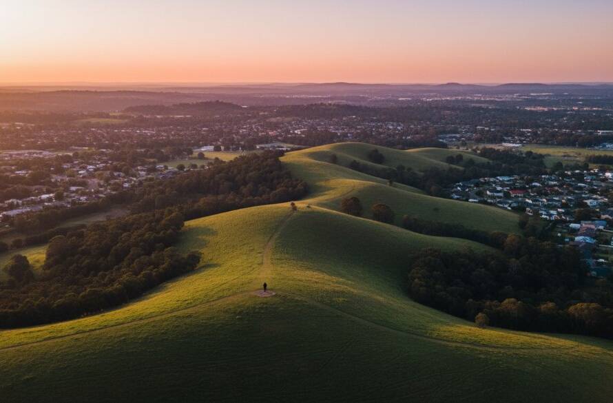 An epic high-angle drone shot capturing the Dandenong Ranges meeting residential Croydon South, bathed in golden hour light, showcasing the stunning aerial views Croydon South drone photography can achieve, with a family silhouetted enjoying the panorama.