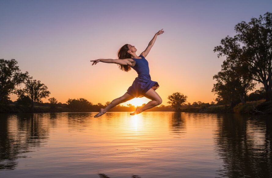 A dynamic and elegant Swan Hill dance photography capturing graceful movement of a professional contemporary dancer mid-air, silhouetted against a golden hour sunset over the Murray River, showcasing power and elegance with professional lighting.