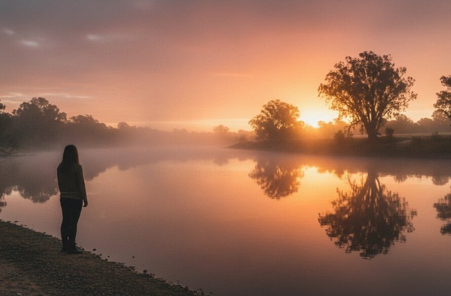 A breathtaking high-angle wide shot showcasing Swan Hill Murray River fine art portraiture, featuring a solitary figure silhouetted against a golden sunrise over the majestic riverbend, evoking a sense of calm and deep introspection, professionally color-graded.