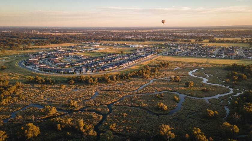 A wide, dramatic Tarneit drone photography breathtaking aerial views shot, showcasing a vibrant sunset over the newly developed Tarneit gardens with modern homes below, highlighting the expansive urban landscape meeting natural beauty, captured with cinematic flair.