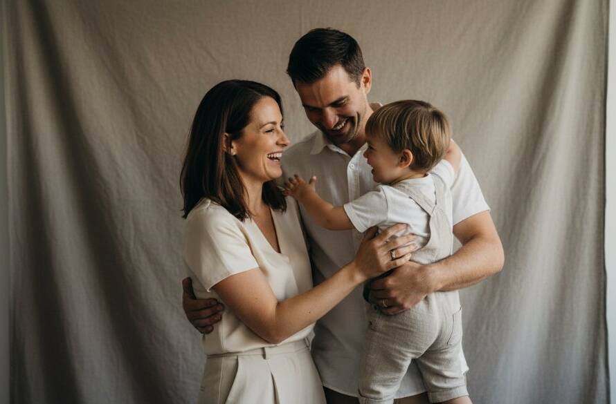 A heartwarming, candid photograph of a family embracing and laughing joyfully in a modern studio setting, capturing their unique bond for timeless family studio portraits Wantirna Victoria. Dramatic, soft lighting illuminates their faces, evoking a sense of enduring love and happiness.