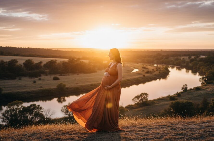 A glowing pregnant woman, elegantly draped, stands silhouetted against a golden Mooroopna sunset, embodying a timeless Mooroopna outdoor maternity photoshoot. Her hand cradles her belly, capturing an epic, emotional moment in nature with dramatic light.