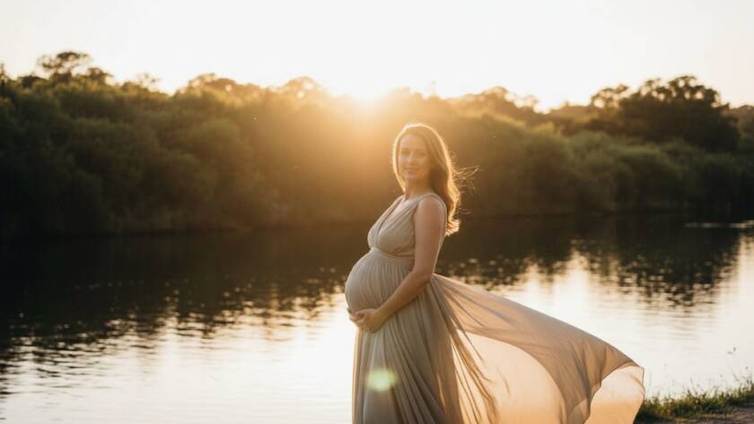 A breathtaking portrait from timeless outdoor maternity photography Bulleen Victoria, featuring a radiant pregnant woman silhouetted against a golden hour sunset over the Yarra River, capturing an epic moment of serene anticipation and natural beauty.