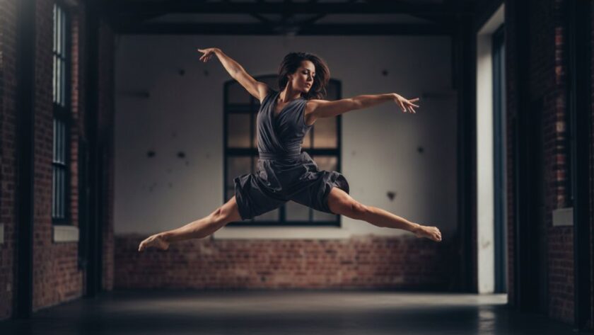 An epic moment in Traralgon dance photography capturing dynamic artistry, featuring a dancer mid-leap against a dramatic, moody backdrop, illuminated by theatrical lighting to highlight their powerful silhouette and graceful movement.