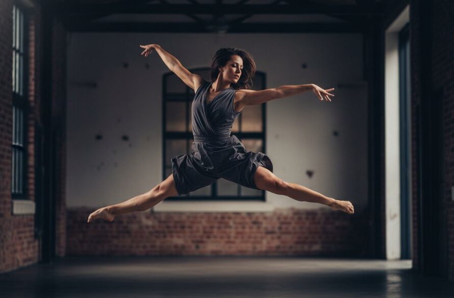 An epic moment in Traralgon dance photography capturing dynamic artistry, featuring a dancer mid-leap against a dramatic, moody backdrop, illuminated by theatrical lighting to highlight their powerful silhouette and graceful movement.
