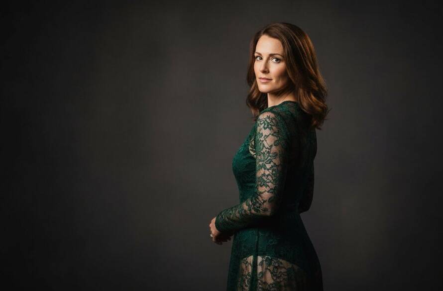 A dramatic and artfully lit close-up of a woman in a elegant black lace robe, captured during a Vermont South boudoir photography for empowering self-love session, her gaze confident and serene, with soft focus on her silhouette against a subtly textured wall, evoking a sense of powerful self-acceptance.