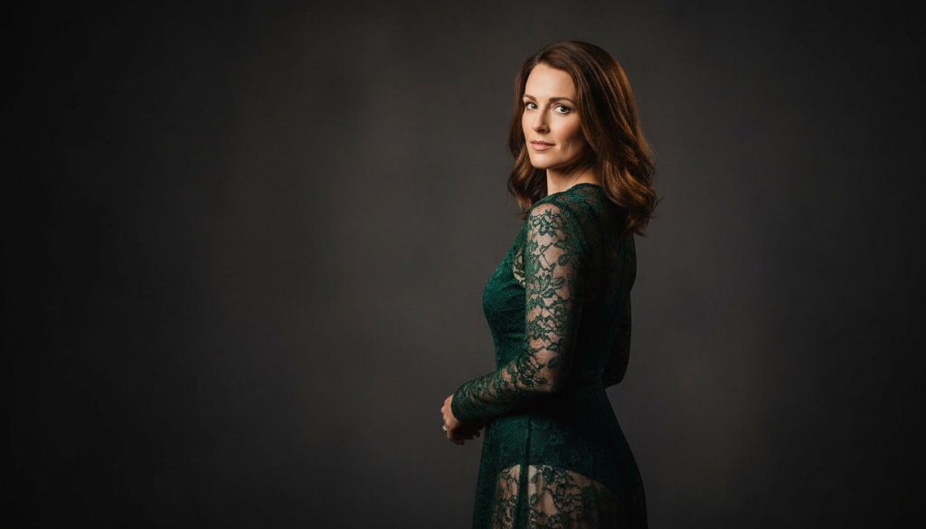 A dramatic and artfully lit close-up of a woman in a elegant black lace robe, captured during a Vermont South boudoir photography for empowering self-love session, her gaze confident and serene, with soft focus on her silhouette against a subtly textured wall, evoking a sense of powerful self-acceptance.