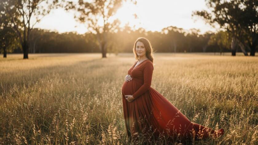 A pregnant woman, bathed in the soft glow of golden hour light in a scenic Vermont South park, posing elegantly for Vermont South maternity photography outdoor golden hour, creating an epic, serene portrait.