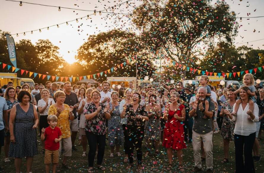 An epic, joy-filled moment captured with vibrant Hillside community event photography, showing a group of diverse attendees cheering under dramatic festival lights at a local Hillside park in Victoria, professionally colour graded.