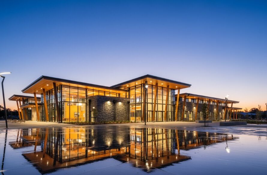 A wide, dramatic shot capturing the Wallan Victoria commercial architecture photography impact of a newly built, modern community centre at dusk, with warm interior lights glowing and a dynamic sky above, highlighting its contemporary design and welcoming presence.