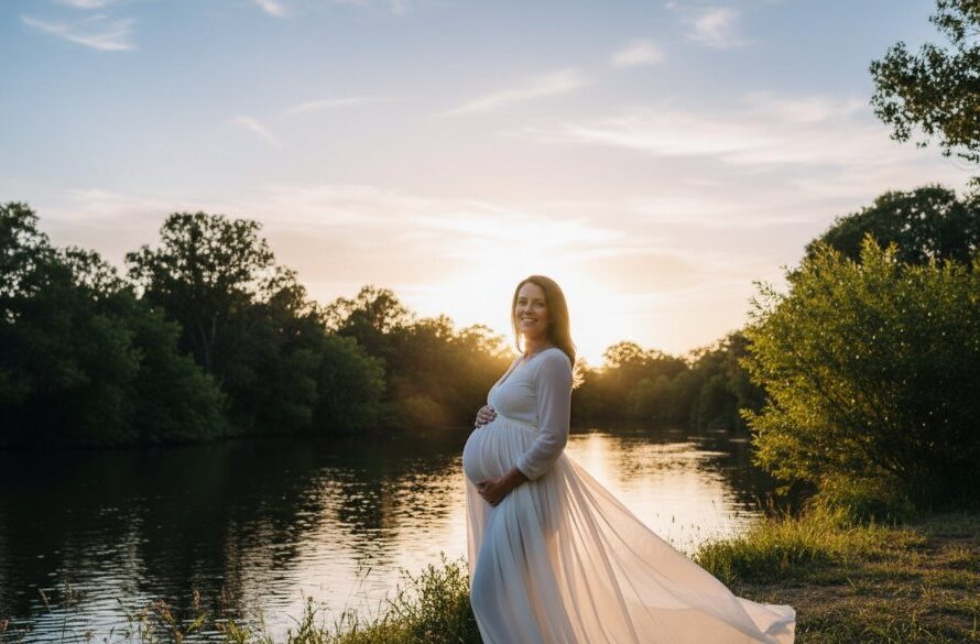 A stunning wide shot of a glowing pregnant woman at sunset by the Ovens River in Wangaratta, capturing ethereal Wangaratta twilight maternity photos with natural light, with dramatic golden hour backlighting and a serene, joyful expression.