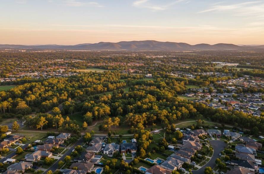 A stunning aerial panoramic view of Wantirna's green landscapes meeting suburban rooftops at sunset, expertly captured through Wantirna drone photography capturing unique aerial perspectives, with dramatic golden hour light illuminating a local park and distant Dandenong Ranges.