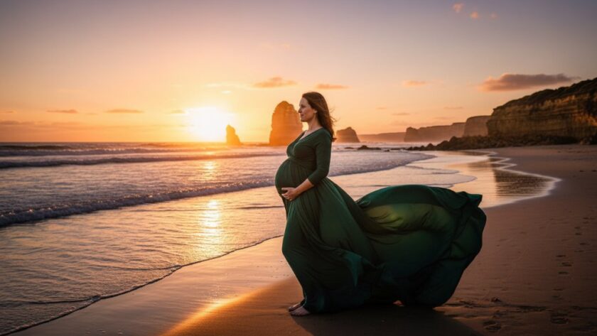 A wide, epic shot of a pregnant woman in a flowing, deep teal dress, silhouetted against a dramatic sunset over the Southern Ocean at Warrnambool, radiating an ethereal glow during her Warrnambool beach maternity photoshoot ethereal glowing session. Waves gently break on the shore, casting a serene and powerful mood.