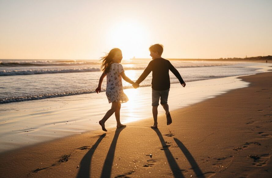 A wide-angle, low-angle professional photograph capturing Warrnambool kids photography epic moments capturing joy, showing two children joyfully running along the sandy shores of Warrnambool Beach at sunset, with dramatic golden light, crashing waves, and the iconic breakwater in the distance, evoking genuine happiness.
