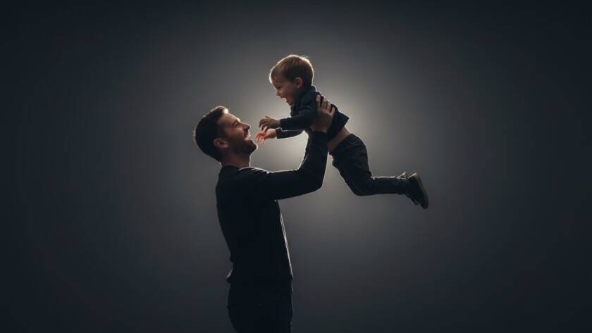 A powerful, cinematic black and white portrait of a mother and child embracing warmly in a sunlit Williamstown studio, capturing an intimate Williamstown studio portrait photography experience with dramatic shadows and highlights.