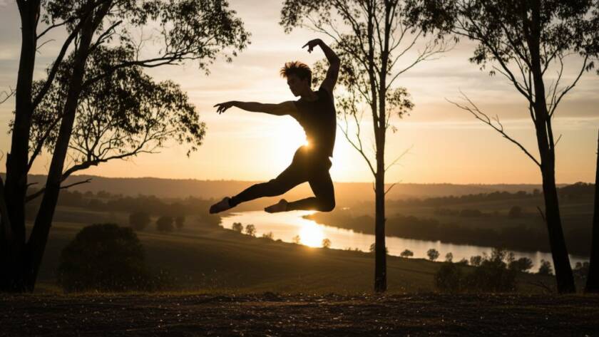 An epic moment captured in Wonga Park contemporary dance photography artistry, featuring a dancer mid-air in a dramatic leap against the soft, golden light of a Wonga Park sunset, evoking power and grace.
