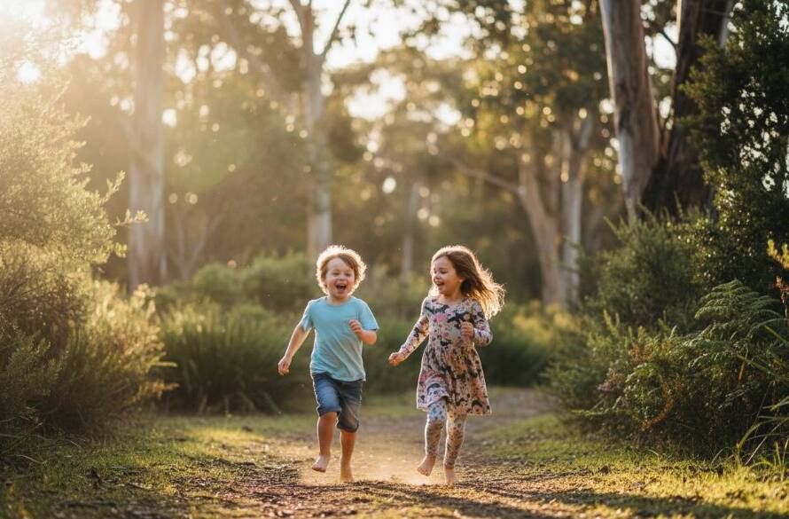 A wide shot of two children laughing joyously while exploring a sun-dappled trail in Wonga Park, capturing their Wonga Park natural kids photography adventures with golden hour light.