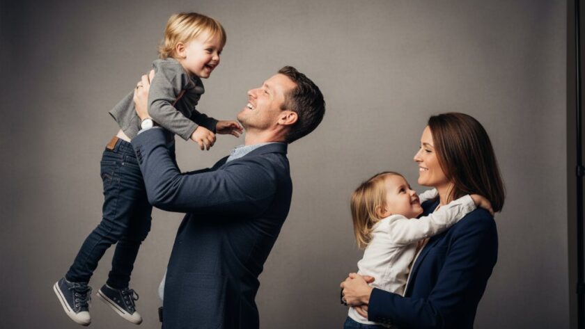A family of four, parents and two children, sharing a joyful, candid moment in a professionally lit Yarrawonga bespoke studio photography experience, captured with dramatic lighting and professional color grading.
