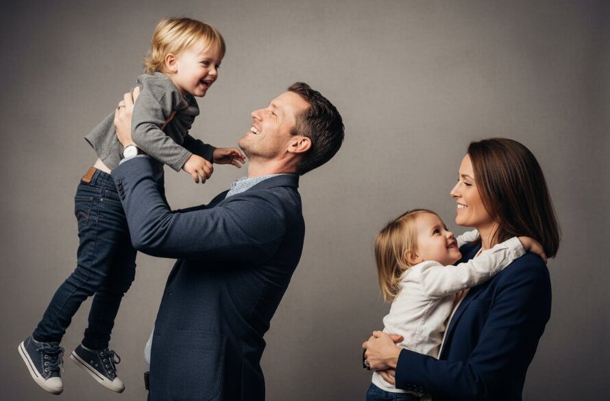 A family of four, parents and two children, sharing a joyful, candid moment in a professionally lit Yarrawonga bespoke studio photography experience, captured with dramatic lighting and professional color grading.